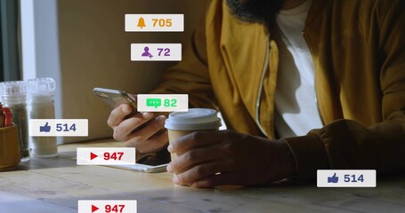 Holding paper cup and checking smartphone, man in mustard jacket at wood table with social badges