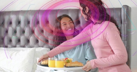 Leaning woman placing white breakfast tray on duvet at bedroom, wearing pink top, with orange juice © vectorfusionart