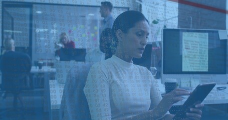 Fototapeta premium Using tablet, mid-adult woman in turtleneck tapping screen in tech office, with numeric overlay