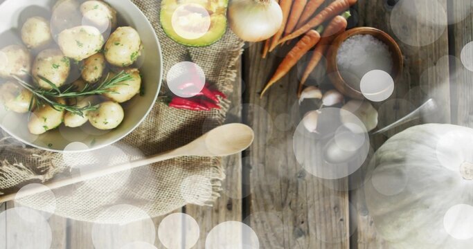 Showing white bowl of seasoned potatoes with rosemary on rustic table, avocado, carrots, copy space