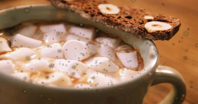 Sitting ceramic mug holding hot cocoa with soft marshmallows and biscotti on wooden table, drizzled