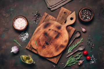 Dark culinary background with empty wooden cutting boards and spices. Top view, flat lay, copy space.