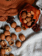Walnuts in small wicker basket on knitted textile background. Concept of autumn food background, cozy still life with copy space for packaging, banner, social media.