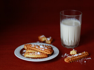 Butter cookies on plate with glass of milk on dark background. Concept of cozy snack moment, homemade dessert, copy space background for food blog, banner, social media.