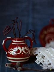 Traditional ceramic jug with decorative pattern on textile background. Concept of folk culture still life, rustic home decor, copy space background for editorial and design use.