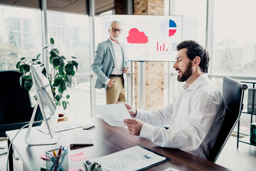 Business meeting in modern office with two colleagues discussing reports and charts during a...