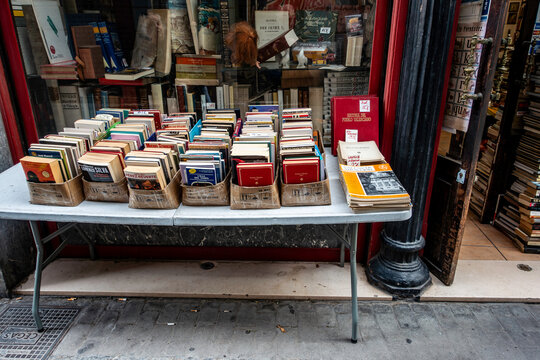 Secondhand books for sale on a sidewalk table outside El Asilo del Libro, a historic bookstore in Valencia, Spain, featuring vintage charm and art.