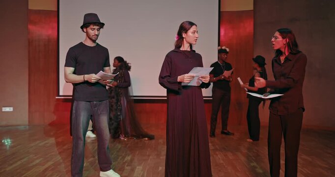 Indian young adult gen z male female hold script paper do acting scene practice indoor hall stage room Teen girl boy group team talk speak read new story line learn next day drama play at studio place