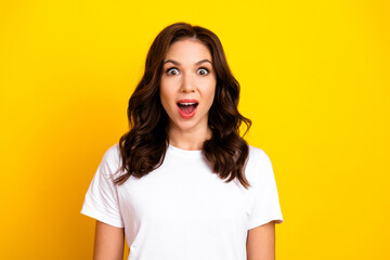 Fototapeta premium Bright surprised brunette woman in white tshirt poses against yellow background for fashion lifestyle image