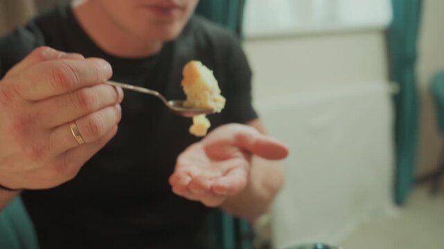 Caucasian man tasting homemade cake at kitchen table, spoon lifting fluffy sponge, closeup of hand and spoon, facial expressions show savor and enjoyment, relaxed after massage and microcurrent