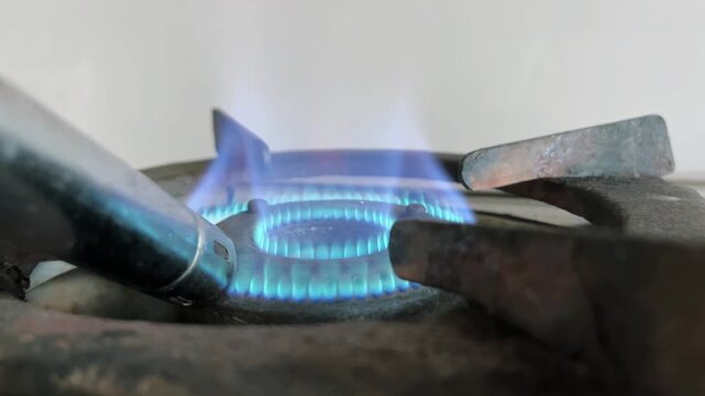 Close up of a kitchen gas stove lighter being used to ignite a stainless steel burner