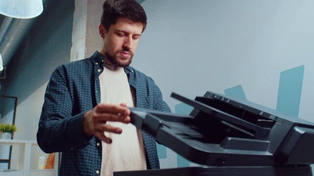 Man using a printer in a modern office setting while preparing to scan documents for work