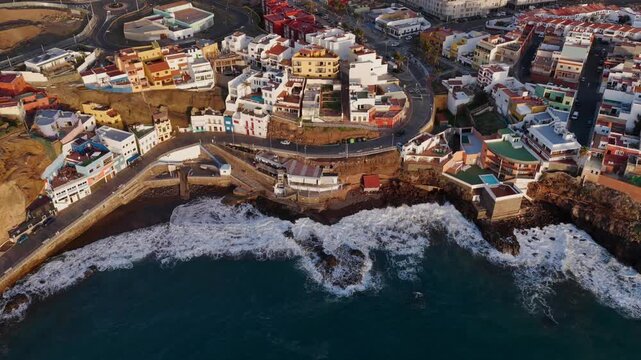 Cinematic aerial sunset over Sardina del Norte lighthouse and colorful coastal village in Gran Canaria