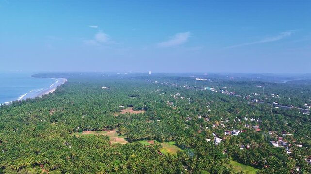 Aerial drone view of Kannur city surrounded by vast green trees and the open Arabian Sea.