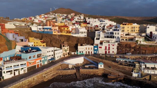 Cinematic aerial sunset over Sardina del Norte lighthouse and colorful coastal village in Gran Canaria
