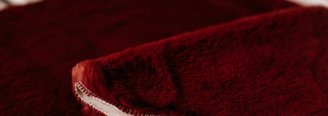Red soft fleece blanket folded with visible stitched edge closeup © Alena Vilgelm