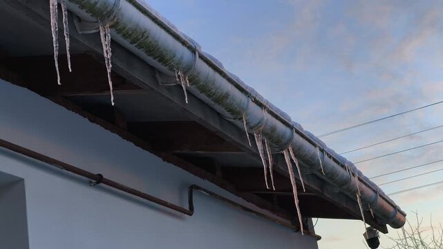 Icicles Hanging from Roof Gutter at Dusk