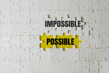 Top view of white jigsaw puzzle with the word Impossible changing to Possible by removing the word Im on yellow background. Business challenge, motivation, success, and overcoming obstacle concept.