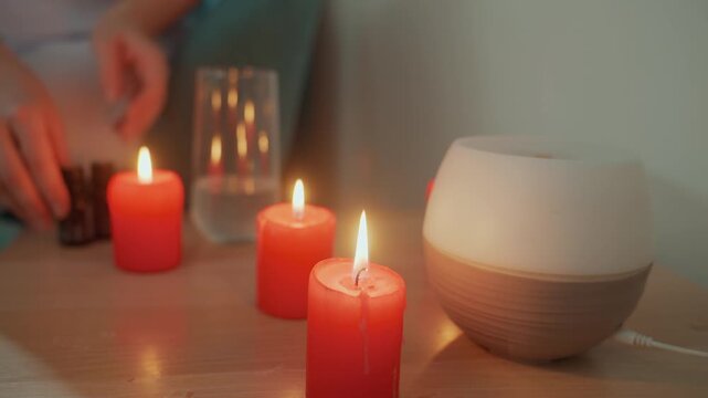 Candle diffuser with gentle light promotes relaxation and tranquility at home. Caucasian woman activates smart diffuser emitting soft yellow illumination for peaceful relaxation environment