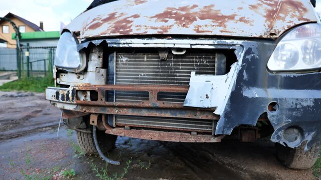 Worn-out, rusty van front with missing bumper, radiator exposed, and peeling paint
