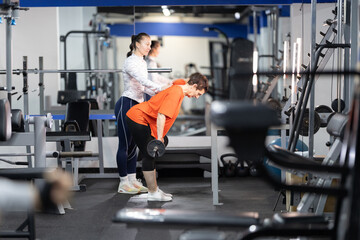 Naklejka premium Personal trainer assisting woman with resistance training in gym