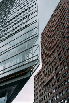 Modern urban office building facade in glass architecture with reflection and angled design shown in a vertical corporate exterior detail view