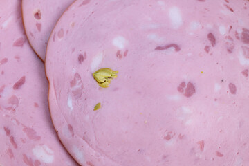 Overlapped sausage slices with pistachio bits, festive platter mood for entertaining with cheese and crackers implied, warm tones and inviting snack presentation for gatherings