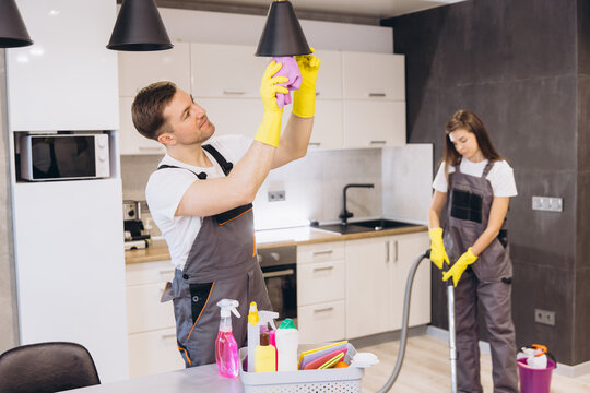 Cleaning company employees cleaning kitchen surfaces and lamp