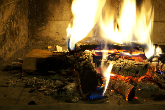 Burning firewood in a fireplace, mantelpiece. Flames fire wooden logs, close-up
