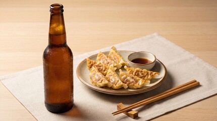 Cold bottled beer served with crispy pan fried gyoza dumplings, soy dipping sauce and chopsticks on a wooden table in a clean minimal Japanese food setting.