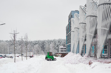 Naklejka premium Tractor clearing snow near building in winter