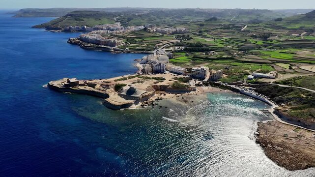 Stunning Aerial View of Qolla l-Bajda Battery and Coastal Salt Pans in Gozo Malta During a Bright Sunny Spring Morning with Deep Blue Mediterranean Waters and Verdant Green Terraced Fields