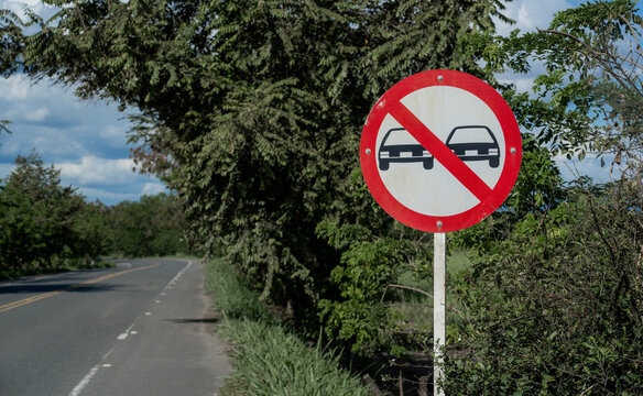 Se&ntilde;al de tr&aacute;fico de prohibido adelantar en carretera rural rodeada de &aacute;rboles y vegetaci&oacute;n