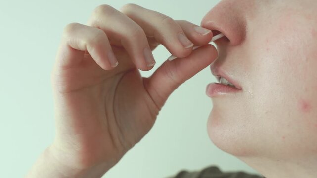A woman performs a nasal swab for a rapid antigen self-test at home, inserting a swab into her nose to collect a sample. Concept of self testing, healthcare, and disease prevention.
