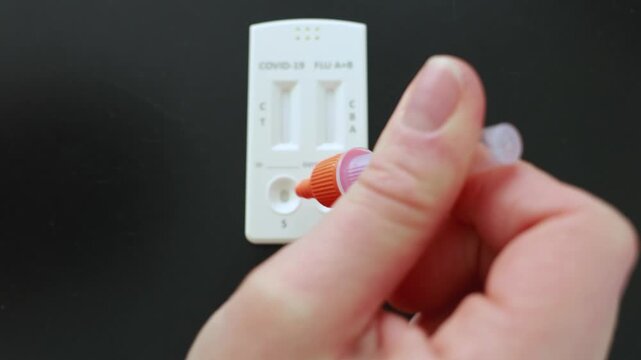 Narva, Estonia &ndash; February 6, 2026: Close-up of a person adding liquid solution to a rapid antigen test cassette as test lines begin to appear. Real home testing process. Editorial use only.
