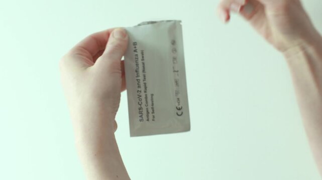 Narva, Estonia &ndash; February 6, 2026: Close-up of a person opening and preparing a rapid antigen self-test kit for COVID-19 and influenza in a real home environment. Editorial use only.