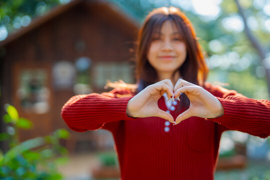  A front view of a cute girl making a heart shape with her hands. (Expression)