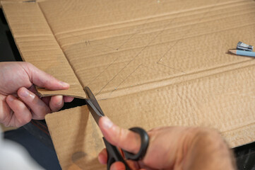 Close-up of hands working on a cardboard prototype at a desk. Startup project concept, product development, prototyping process, creativity, and innovation. Hands-on work, no face visible.