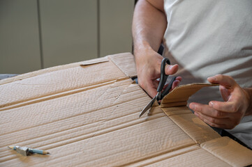 Close-up of hands working on a cardboard prototype at a desk. Startup project concept, product development, prototyping process, creativity, and innovation. Hands-on work, no face visible.