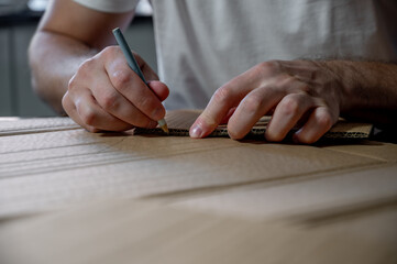 Close-up of hands working on a cardboard prototype at a desk. Startup project concept, product development, prototyping process, creativity, and innovation. Hands-on work, no face visible.