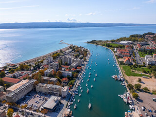 Panoramic aerial view of Omis showing Cetina river mouth, marina with boats, sandy beach and blue Adriatic Sea on a sunny day, Croatia