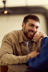 Fototapeta premium Friendly Bearded Man Smiling While Leaning On a Table Across From a Friend in a Diner