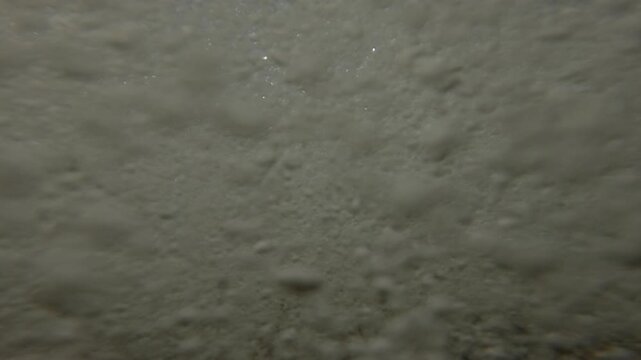 Waves approaching the shore and covers camera and throw pebbles at lens, waves bounce back and cover shore again, Extreme closeup from the bottom level, Underwater view, Slow motion