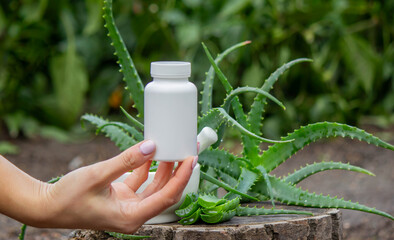 White cosmetic bottle in hand with aloe vera background, product mockup
