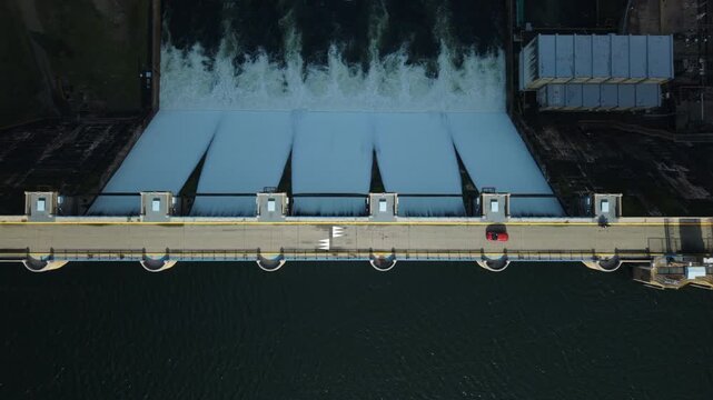 Vista a&eacute;rea de un coche cruzando la presa del embalse de Santa Teresa en Salamanca, Espa&ntilde;a, mostrando una perspectiva cenital del aliviadero, la carretera y la central hidroel&eacute;ctrica.
