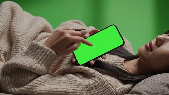 Green Screen young woman at home lying on a couch using with mock up smartphone girl social networks mobile phone pov video footage vertical orientation scene 4 distortion, overlay, glitch, static