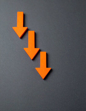Orange wooden arrows pointing downward on dark gray backdrop, business failure and economic loss