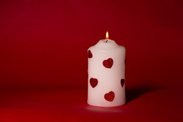 Valentines day minimalists concept. Romantic White Candle with Red Glitter Hearts on Red Background. Valentine Gift Box Wrapped with Red Satin Ribbon and Glitter Hearts