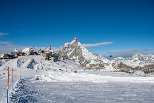 Daytime view of the Plateau Rosa ski area at Testa Grigia, featuring skiers, snow-covered alpine terrain, and the Matterhorn under a clear blue sky.