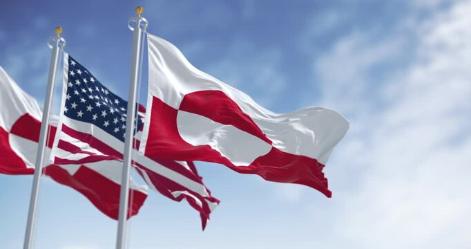 Flags of Greenland and the US waving in the wind on a clear day